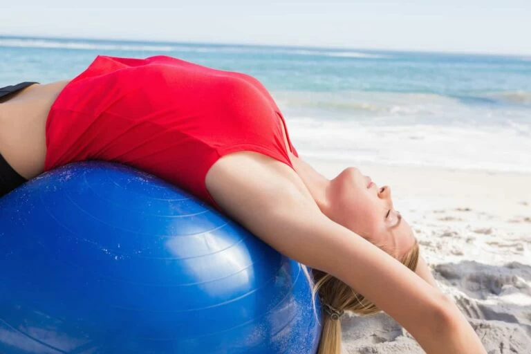 woman lying over ball cracking back